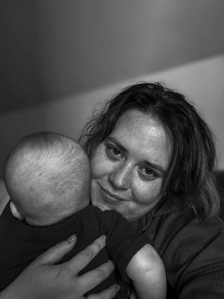 Image of Camille in black and white holding her son, only the back of him is visible.